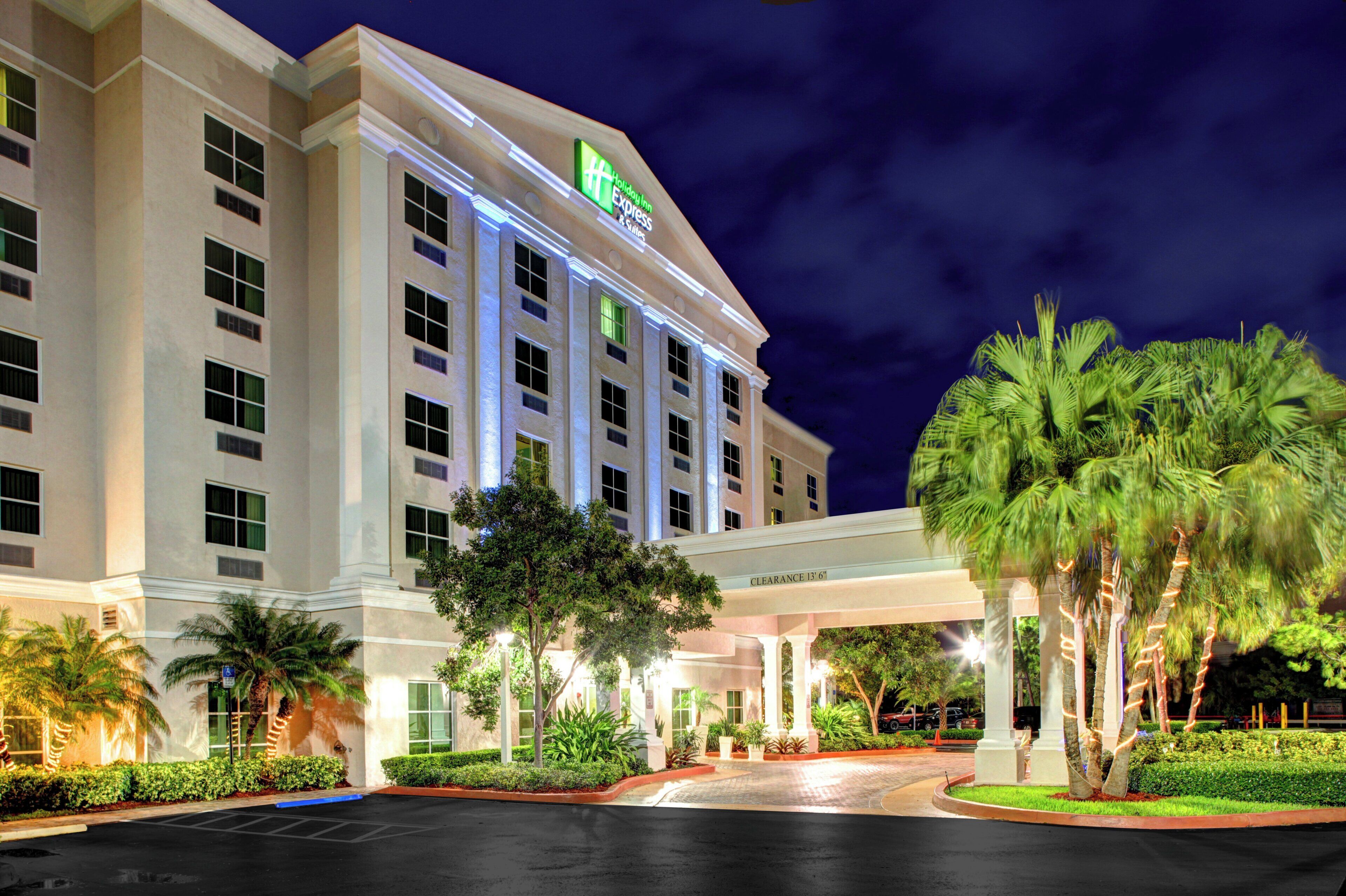 Ein Holiday Inn Express Hotel mit überdachter Eingangspartei und Palmen.