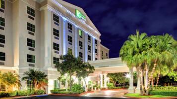 Ein Holiday Inn Express Hotel mit überdachter Eingangspartei und Palmen.