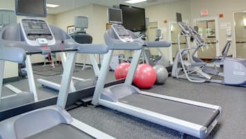 Un gimnasio con cintas de correr, elípticas y pelotas de ejercicio.