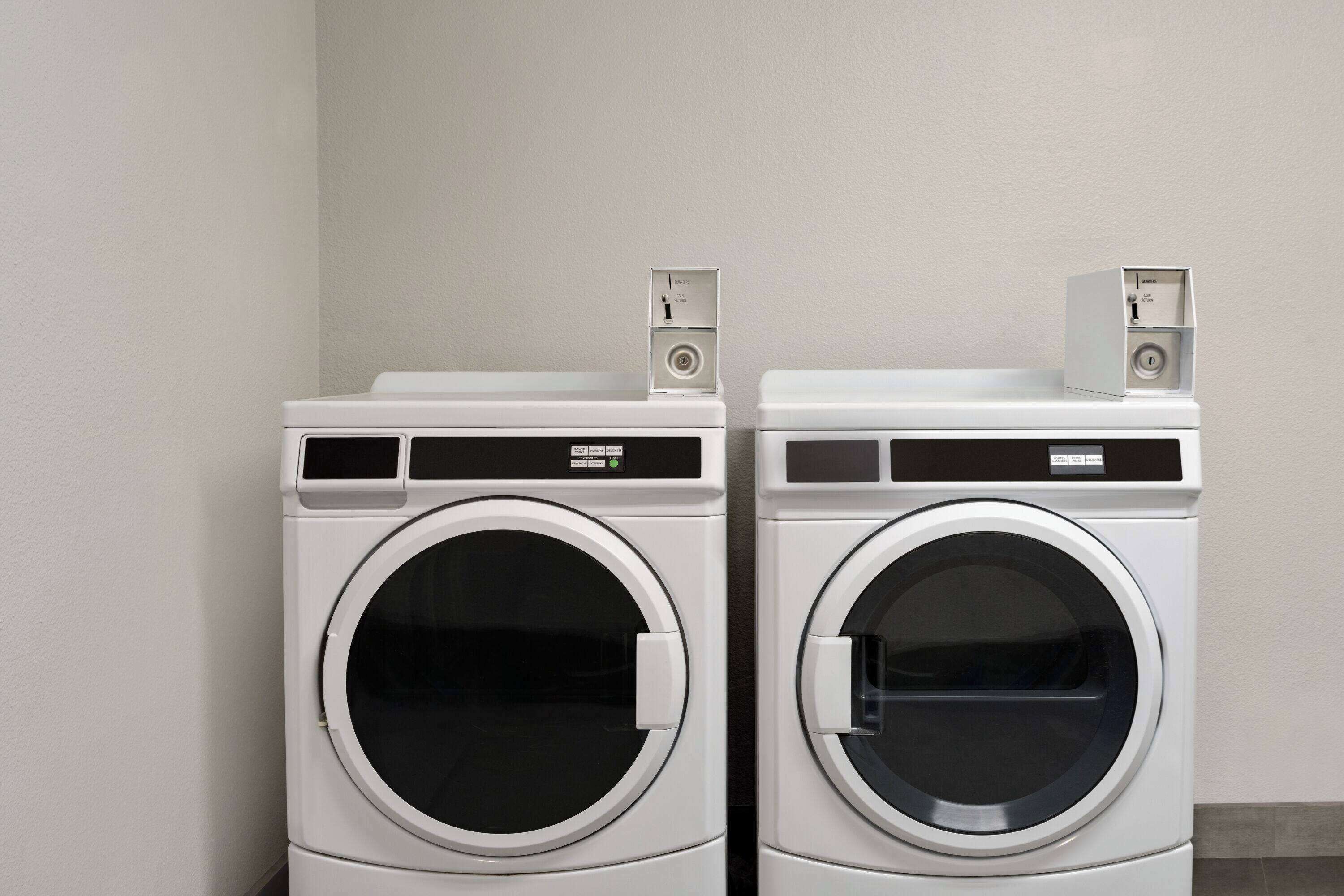 Two stacked front-loading washing machines in a laundry room.
