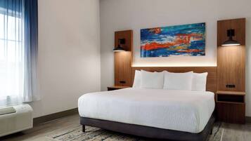 A modern hotel room with a large bed, a painting on the wall, and two bedside lamps.