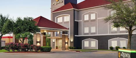 A La Quinta hotel with a modern design, featuring a red roof and a prominent entrance with a covered walkway.
