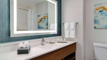 Un baño moderno con un espejo grande, lavamanos blanco y tocador de madera.