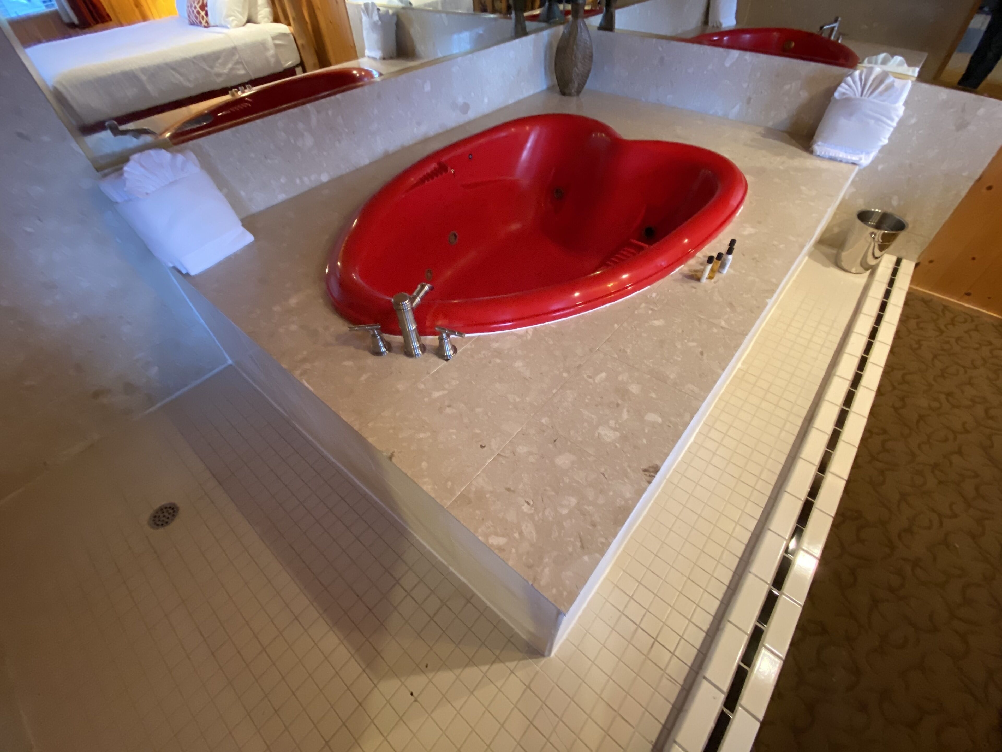 Un baño con una bañera roja grande, un lavabo blanco y un espejo.