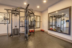 A gym with a mirrored wall, weight racks, and exercise equipment. - Oyen Canalta (Oyen)