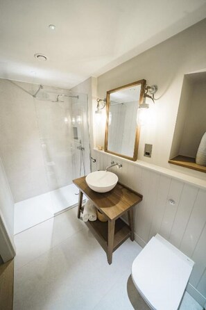 Ein modernes Badezimmer mit einem Holzbettchen, einem großen Spiegel und einer separaten Duschkabine.