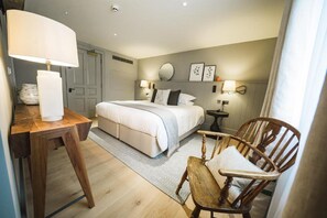 Ein Schlafzimmer mit einem Bett, Nachttischen, einem Sessel und einer Lampe.