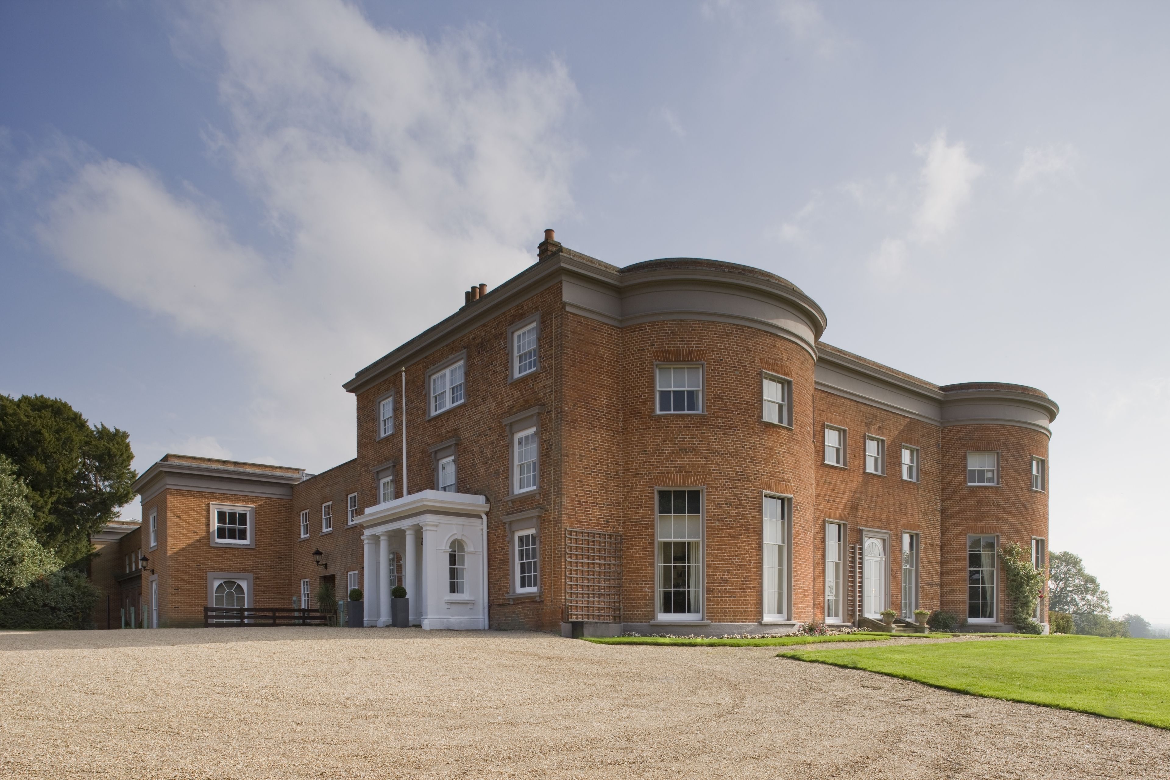 A large, multi-story brick building with a symmetrical facade, multiple windows, and a central entrance with a white portico.