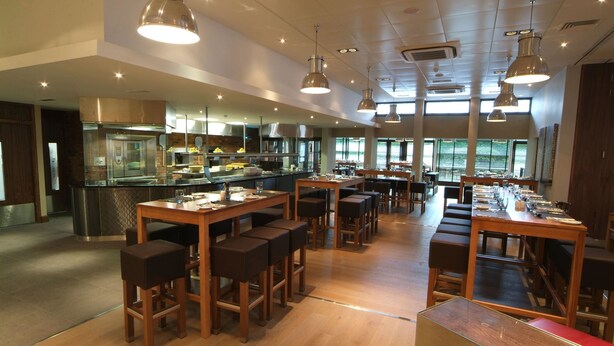A spacious restaurant with high ceilings, pendant lighting, and a long communal dining table. - Denham Grove (Uxbridge)
