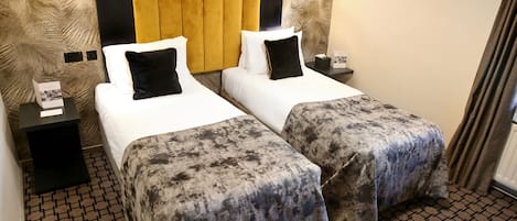 A hotel room with two beds, a patterned carpet, and a headboard with a wooden panel.