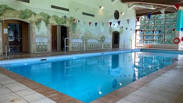 An indoor swimming pool with tiled walls and a wooden ceiling.