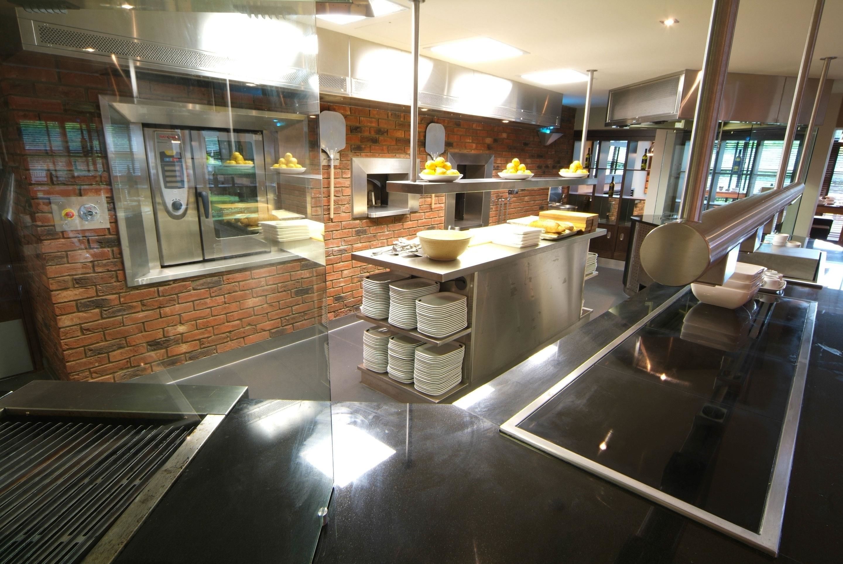 Cocina moderna con electrodomésticos de acero inoxidable, pared de ladrillo y una isla central con cuencos de limones y plátanos.