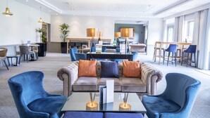 A modern hotel lobby with a plush sofa, blue armchairs, and a glass coffee table. - Denham Grove (Uxbridge)
