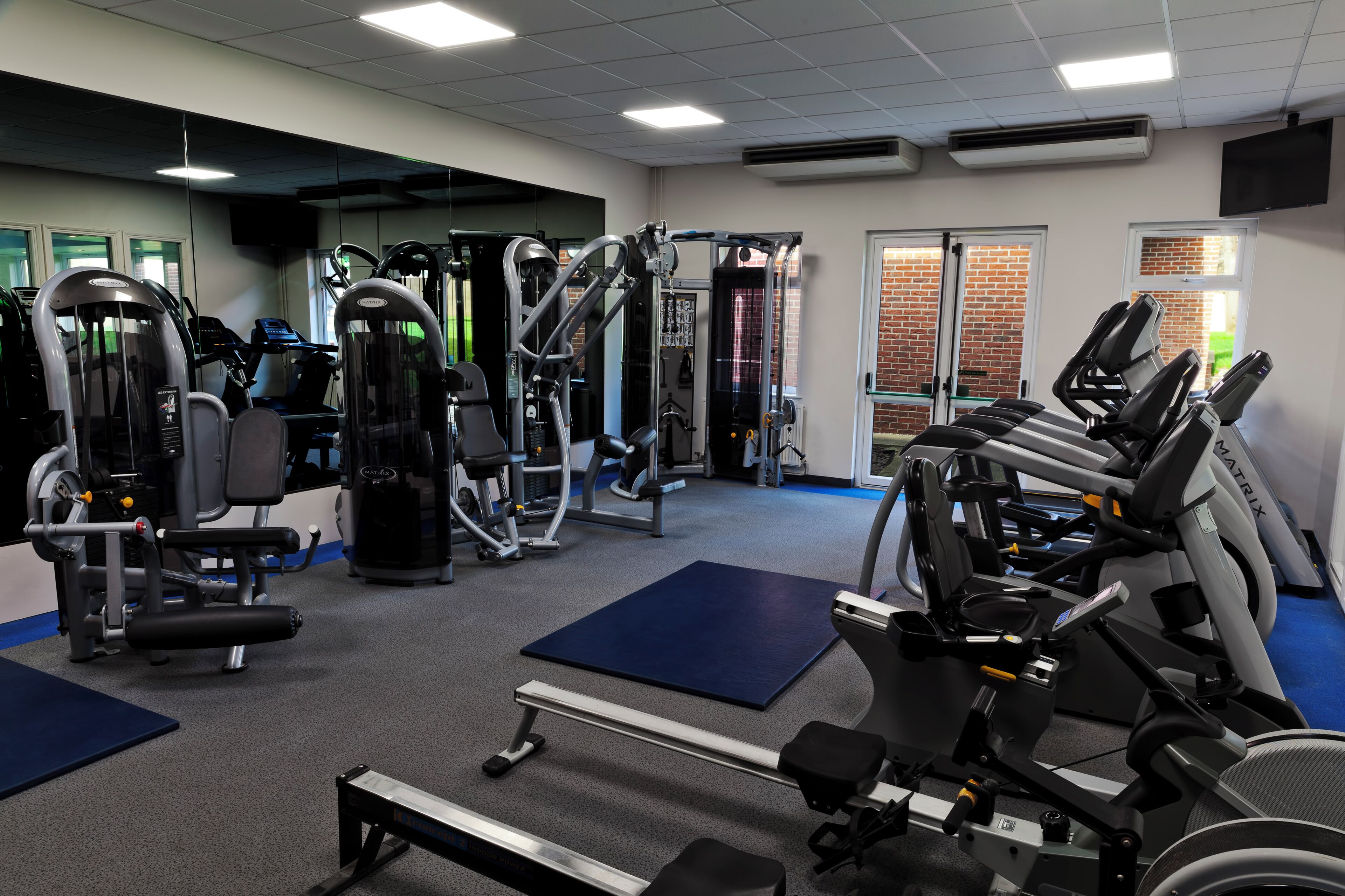 A gym with various exercise equipment, including treadmills, weight machines, and free weights.