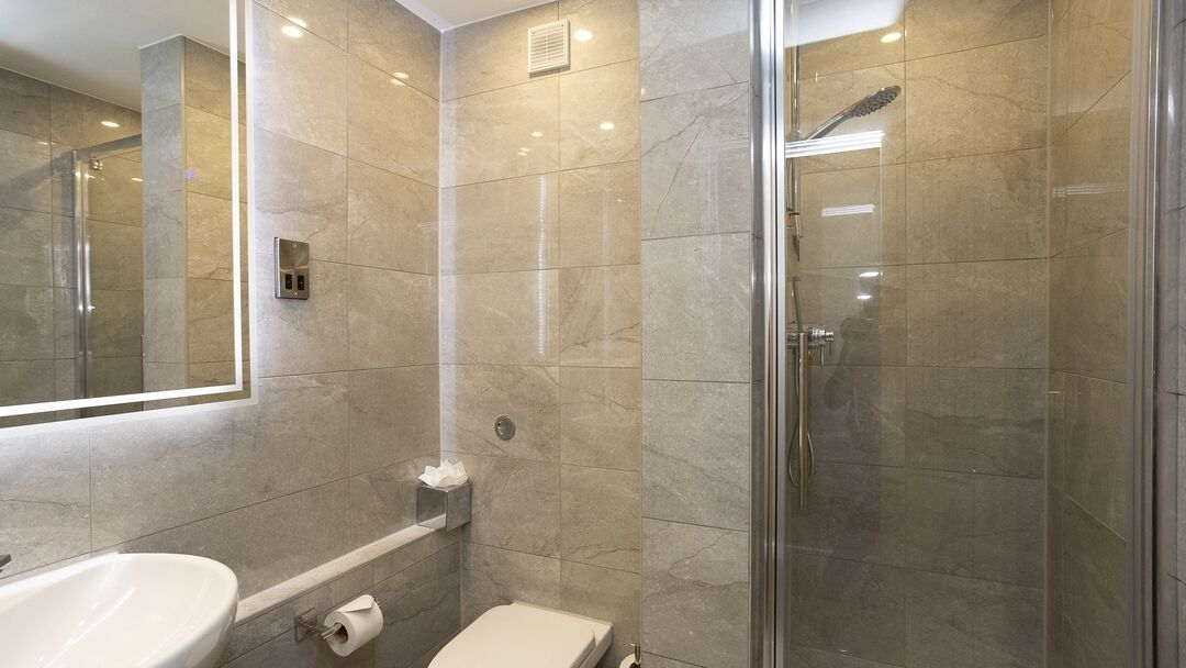 Ein modernes Badezimmer mit Duschkabine aus Glas, Toilette und Waschbecken.