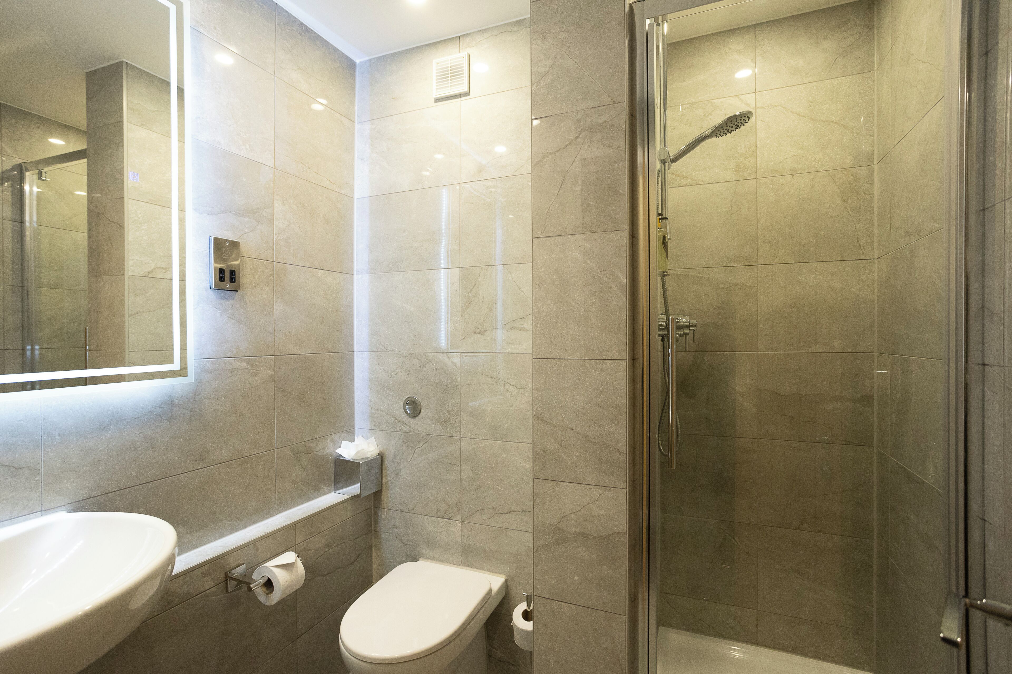 A modern bathroom with a glass-enclosed shower, a sink, and a toilet.