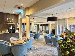 A hotel lobby with seating areas, a coffee machine, and a reception desk. - De Vere Horsley Estate (Leatherhead)