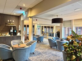 Un hall de hotel con zonas de estar, una máquina de café y un mostrador de recepción.