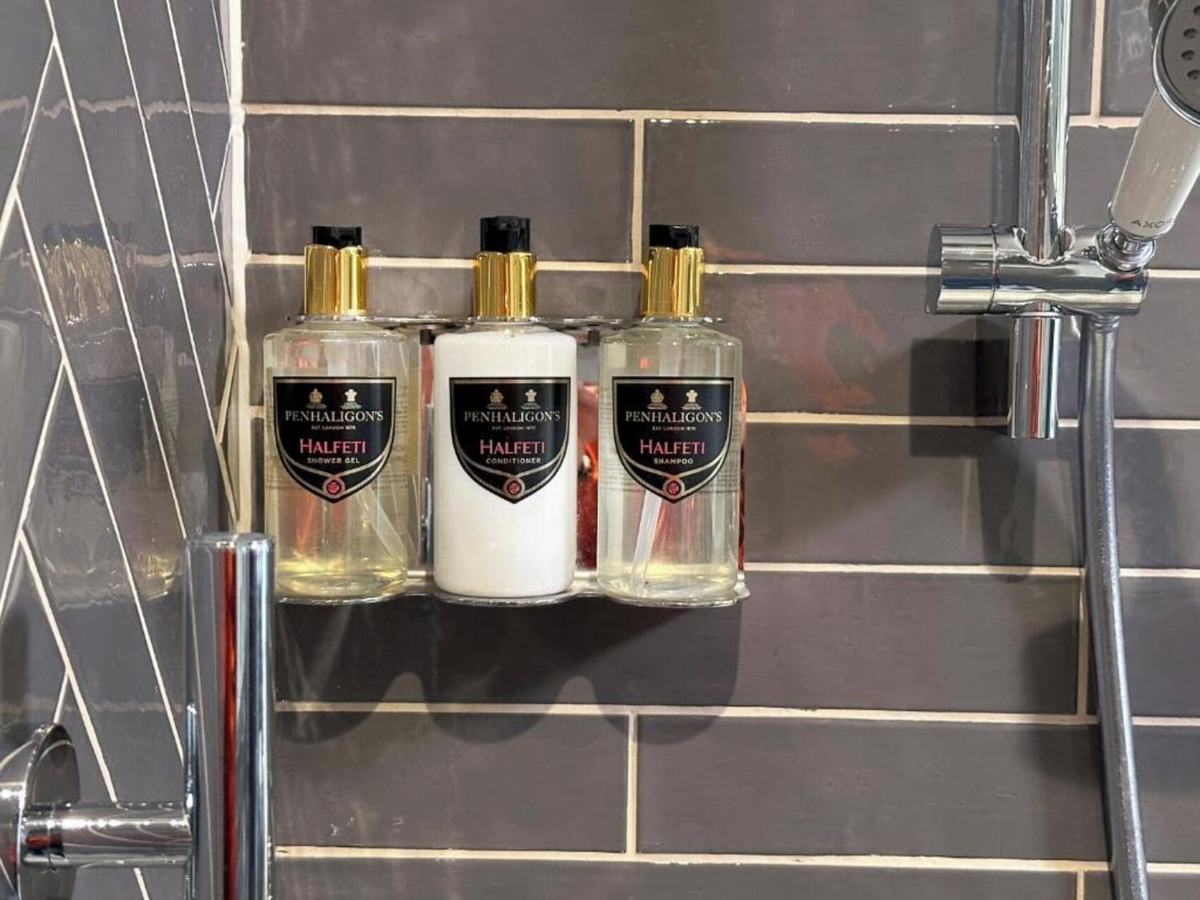 Three bottles of Penhaligon's Halfeti products on a tiled wall.