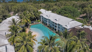 A resort with a large pool surrounded by palm trees and a view of the ocean. - Peppers Beach Club (Port Douglas)