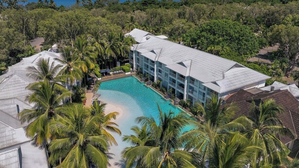 A resort with a large pool surrounded by palm trees and a view of the ocean. - Peppers Beach Club (Port Douglas)