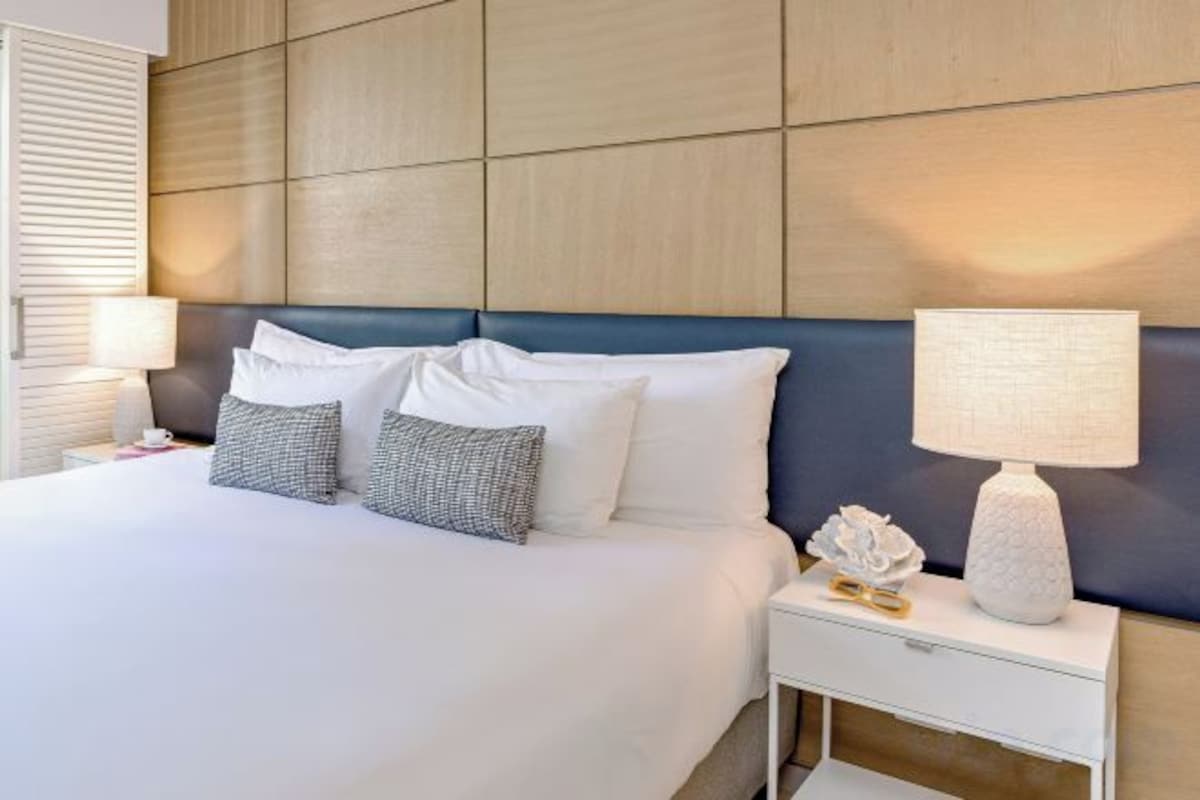 Ett hotellrum med en stor säng, ett nattduksbord med en lampa och en dekorativ prydnad på nattduksbordet.