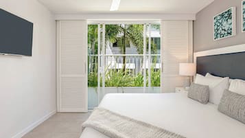 Un dormitorio moderno con una cama grande, ventilador de techo y vistas a zonas verdes a través de una puerta corrediza.