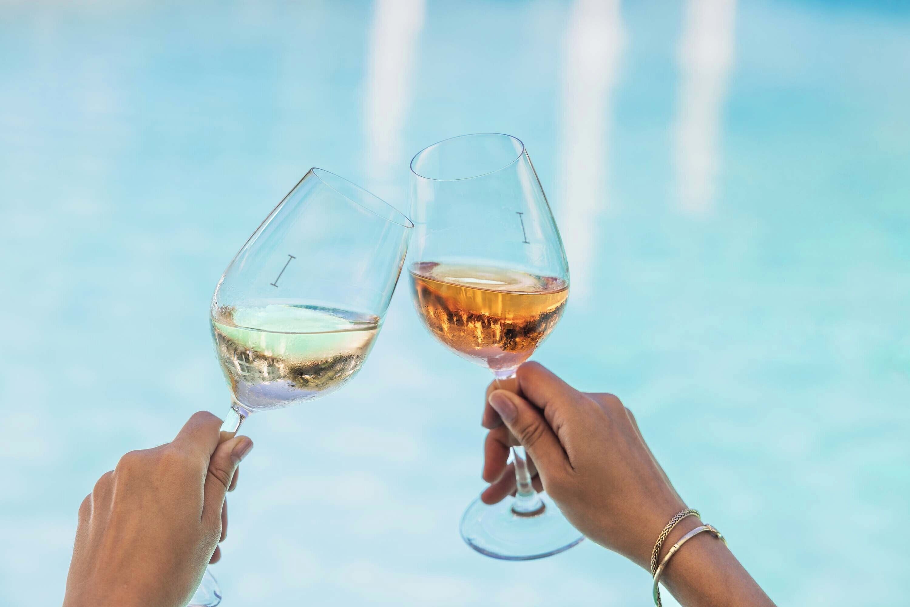 Two hands holding wine glasses with a blurred background.