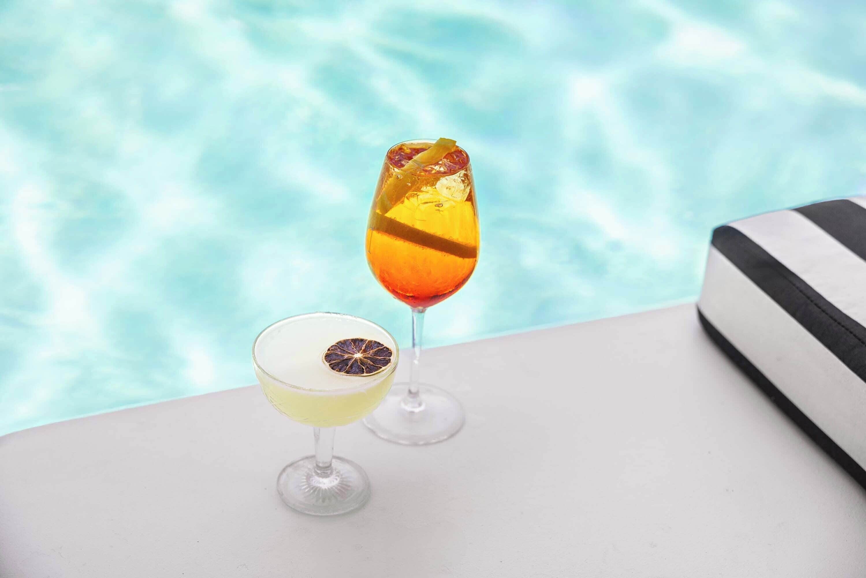 Deux cocktails sur une table, près d’une piscine.