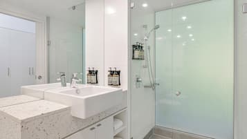 A modern bathroom with a double sink vanity, a glass shower enclosure, and a large mirror.