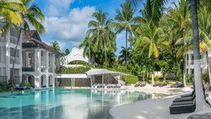 A resort with a swimming pool, palm trees, and a covered seating area. - Peppers Beach Club (Port Douglas)
