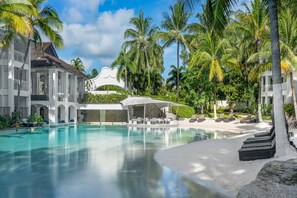 A resort with a swimming pool, palm trees, and a covered seating area. - Peppers Beach Club (Port Douglas)