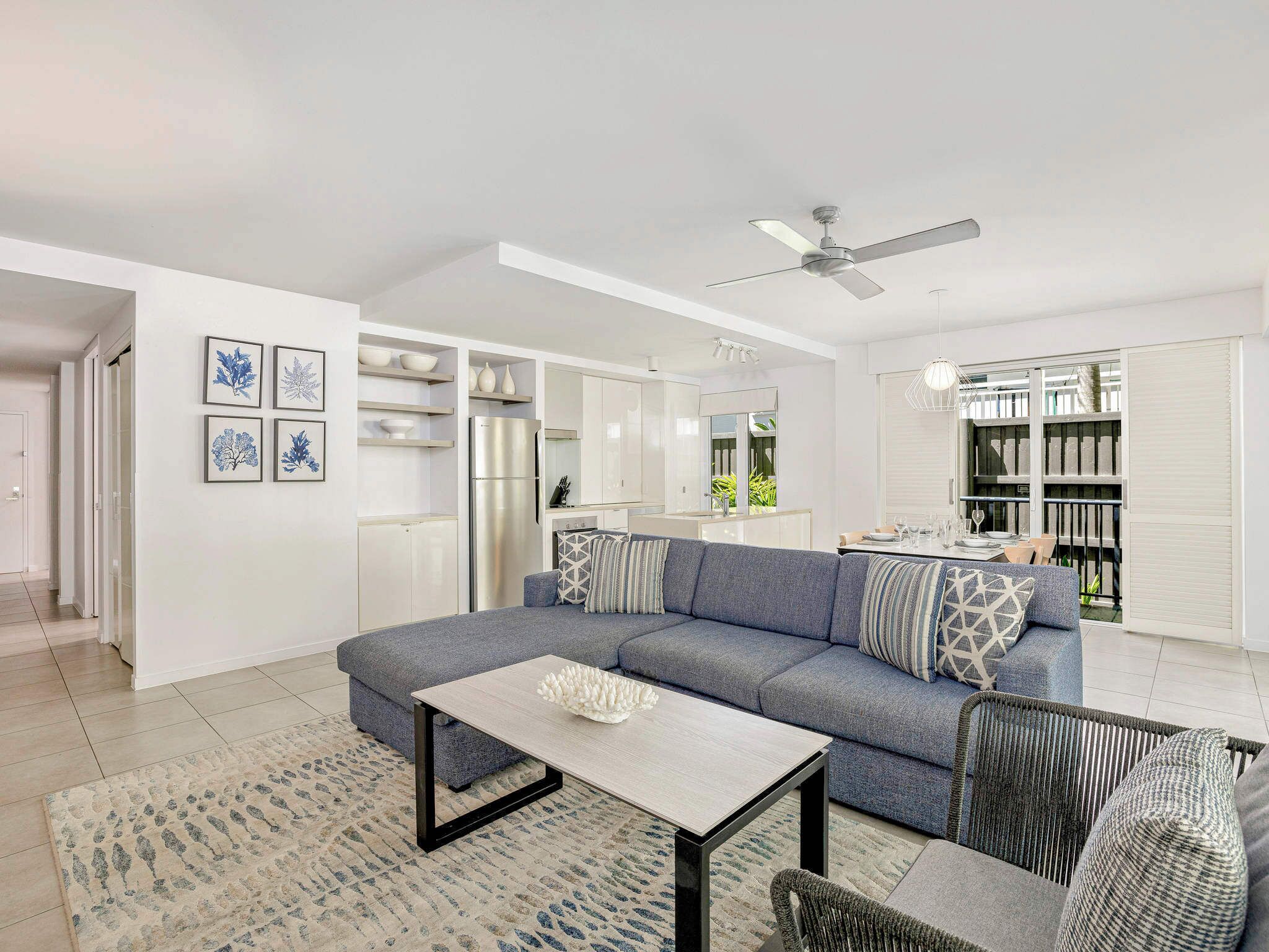 A modern living room with a grey sectional sofa, a coffee table, and a dining area with a table and chairs.
