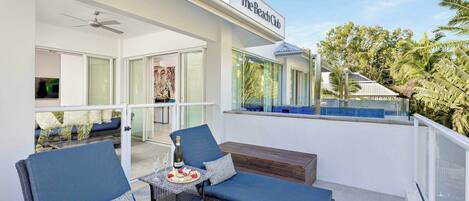 A balcony with wicker furniture, a bottle of champagne, and a glass of wine.