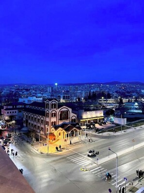Un paisaje urbano al anochecer con un edificio destacado que presenta ventanas en arco y una torre del reloj central.