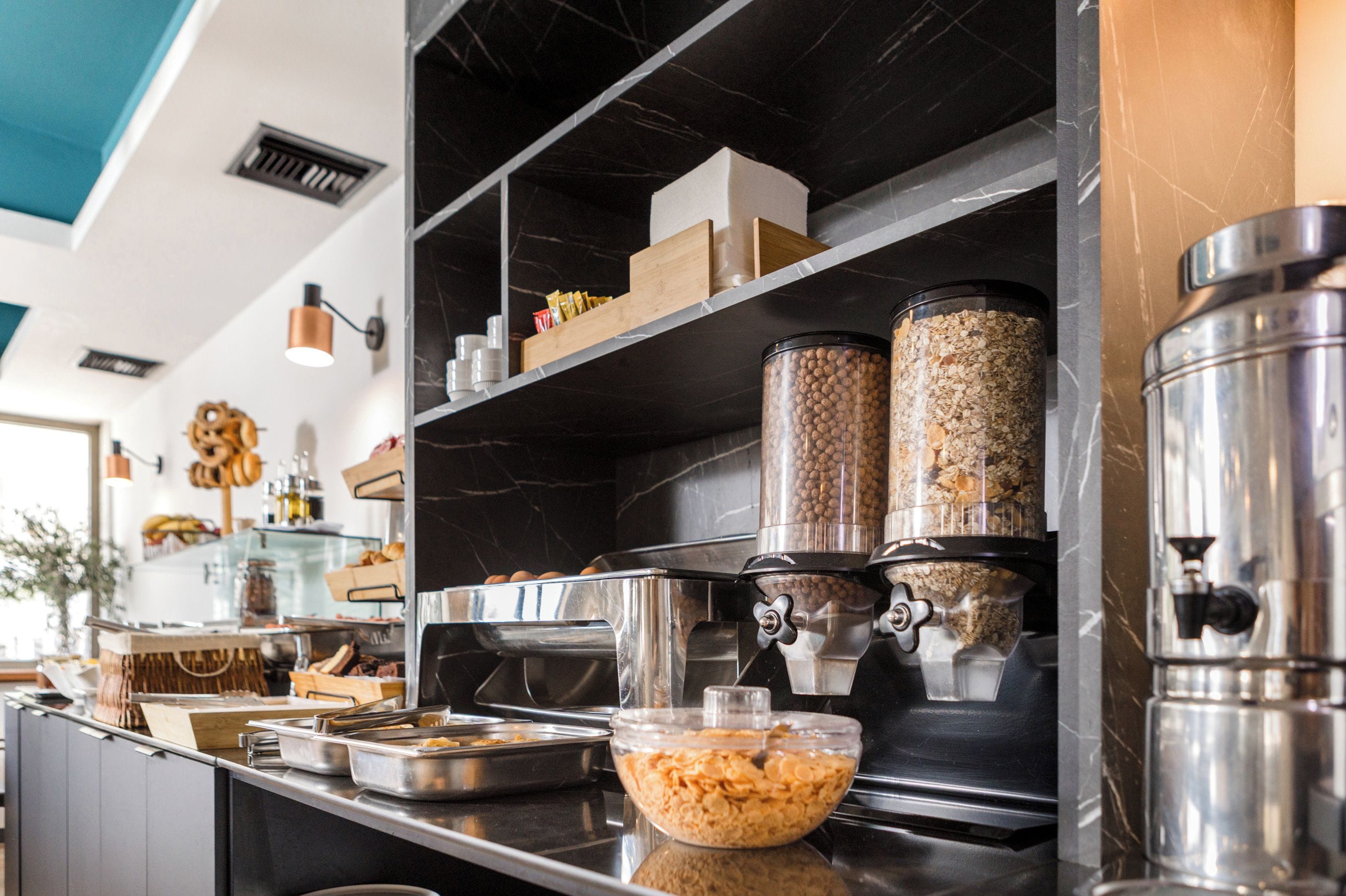 Zona de buffet con diferentes recipientes de comida y una máquina de café.