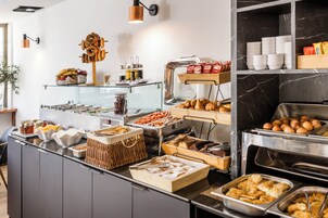 A buffet with various food items, including pastries, hot dogs, and condiments.