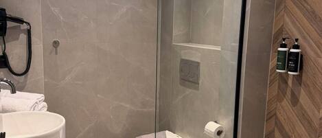 A modern bathroom with a glass-enclosed shower, a white sink, and a wooden wall panel.