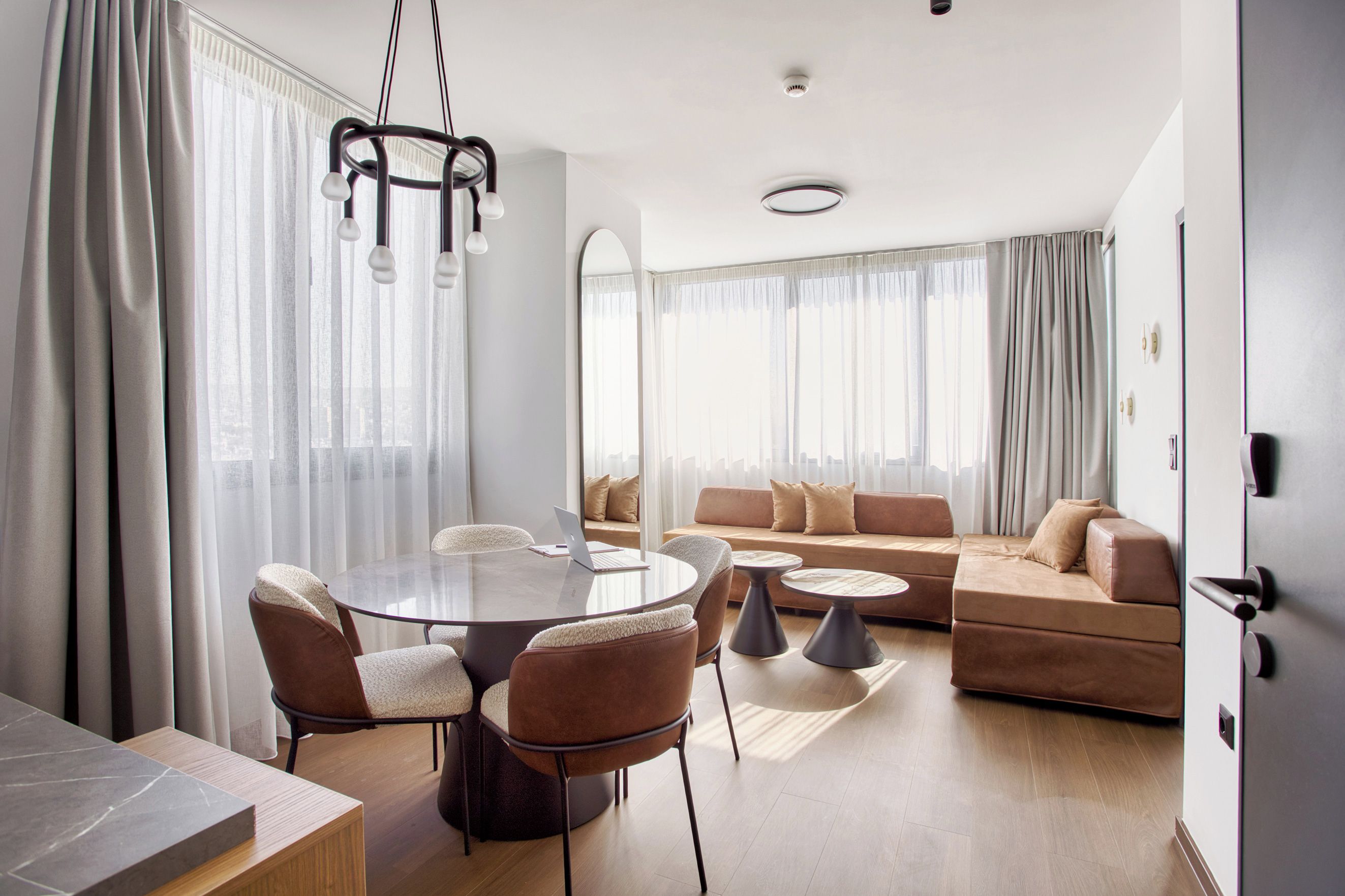 Una sala de estar moderna con una mesa de comedor redonda, sofás y un espejo grande.