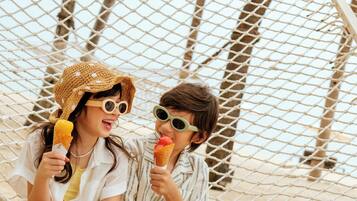 Two people sitting in a hammock on a sandy beach.