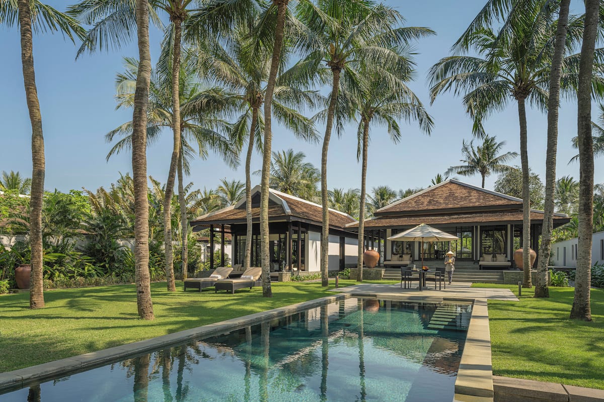 A resort with a swimming pool, palm trees, and lounge areas.