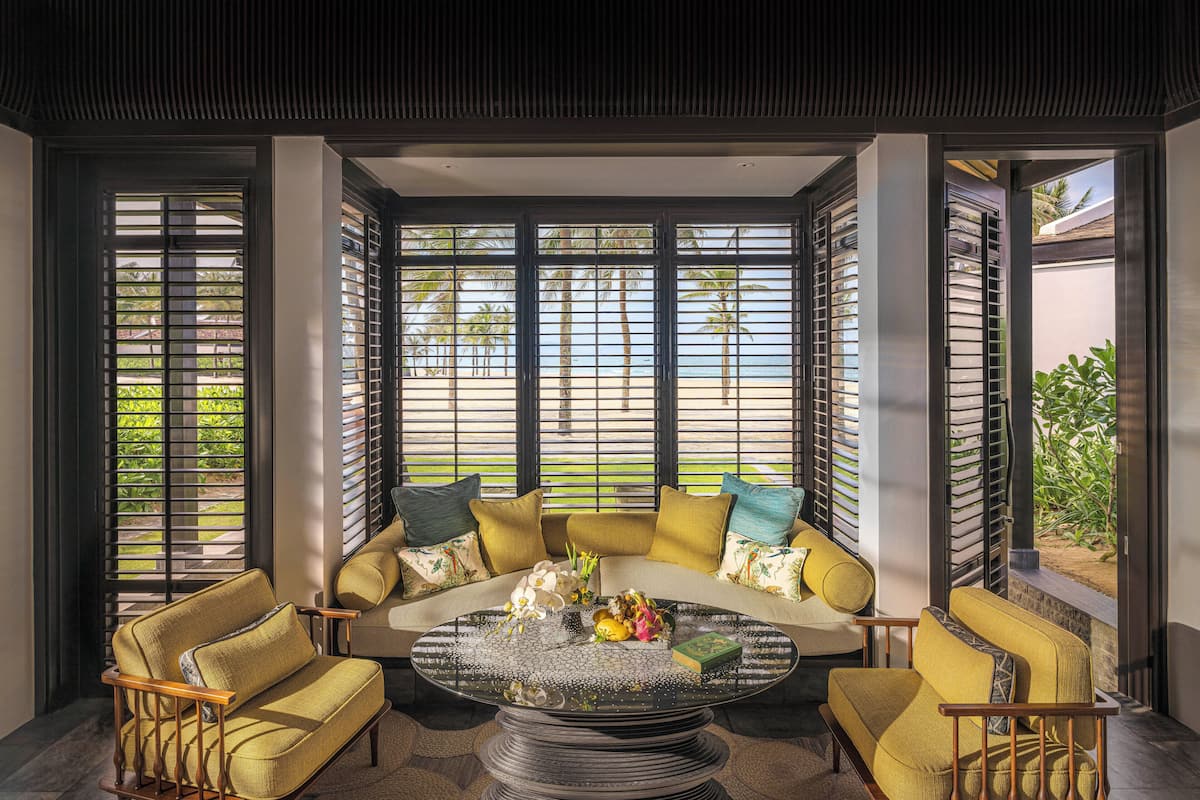 A modern living room with a sofa set, a coffee table, and large windows with blinds.