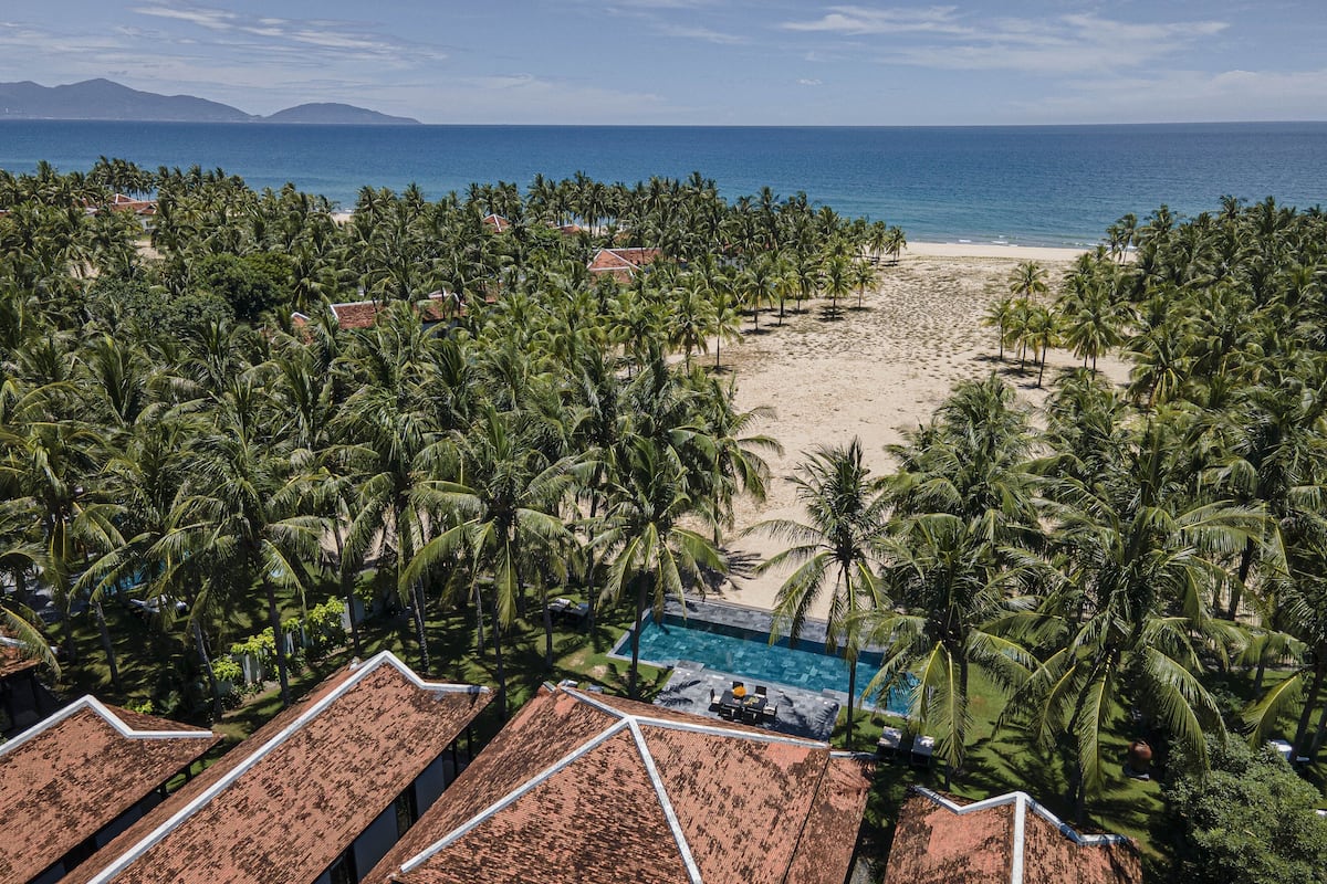 A resort with a beach view, palm trees, and a swimming pool.