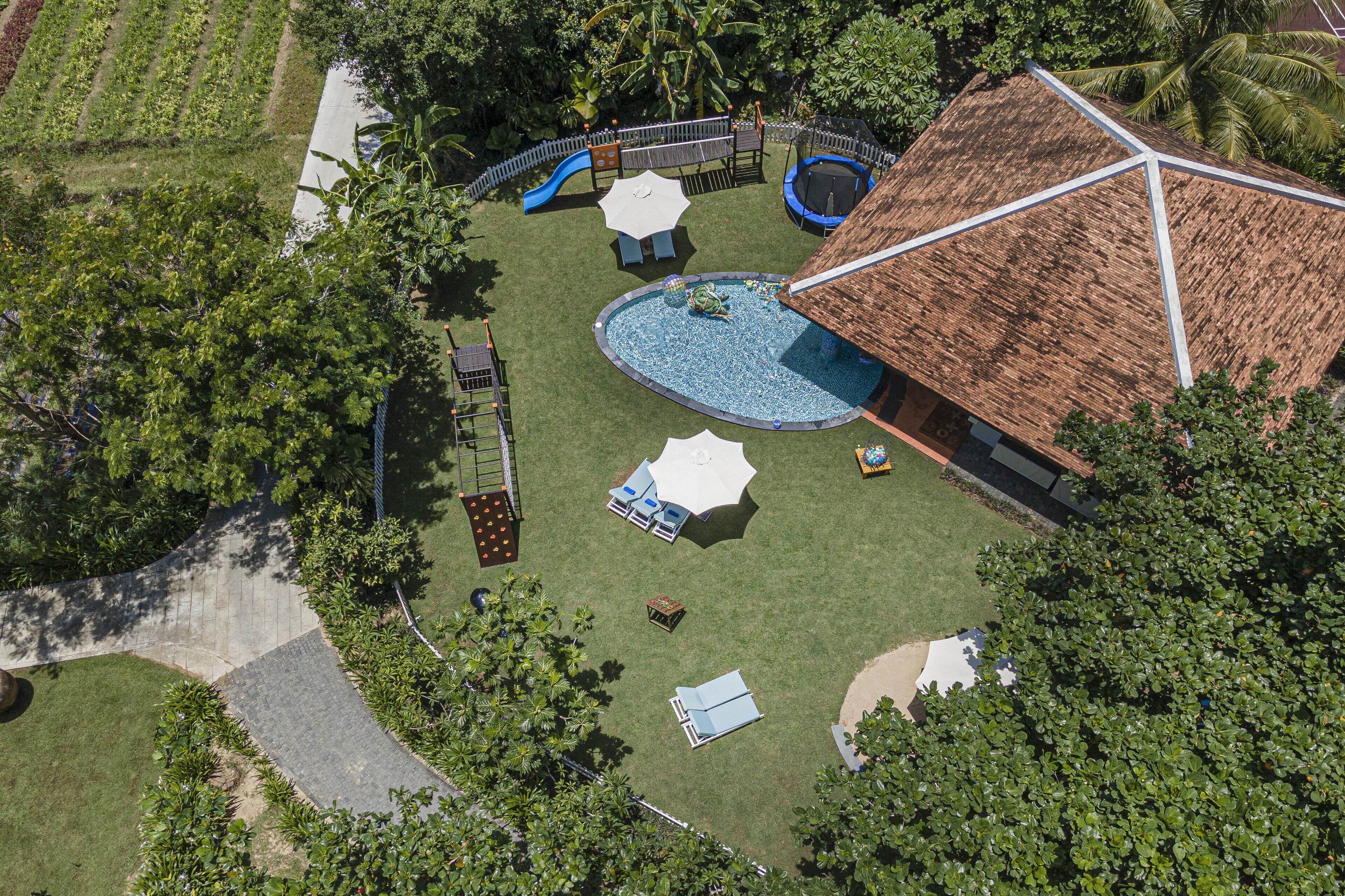 Vista aérea de un parque infantil con toboganes, una piscina y una estructura de techo de paja.