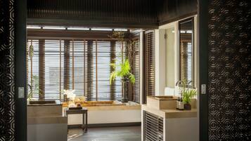 A modern bathroom with a large window, a sink, a mirror, and a potted plant.