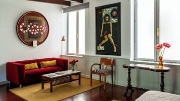 A living room with a red sofa, wooden coffee table, and a painting on the wall.