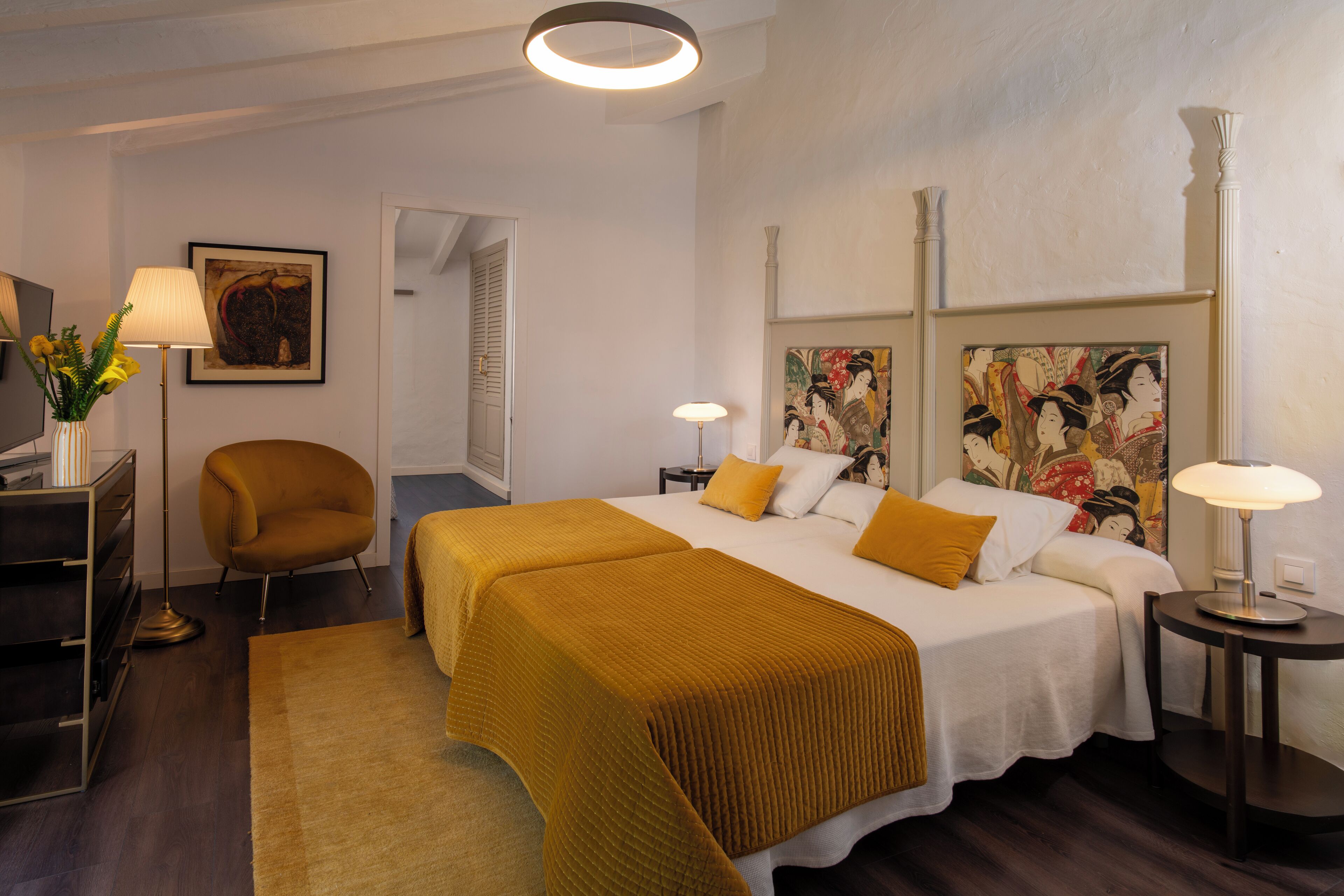 Een hotelkamer met een bed, twee nachtkastjes, een stoel, een bureau en een lamp.