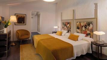 A hotel room with a bed, two bedside tables, a chair, a desk, and a lamp.