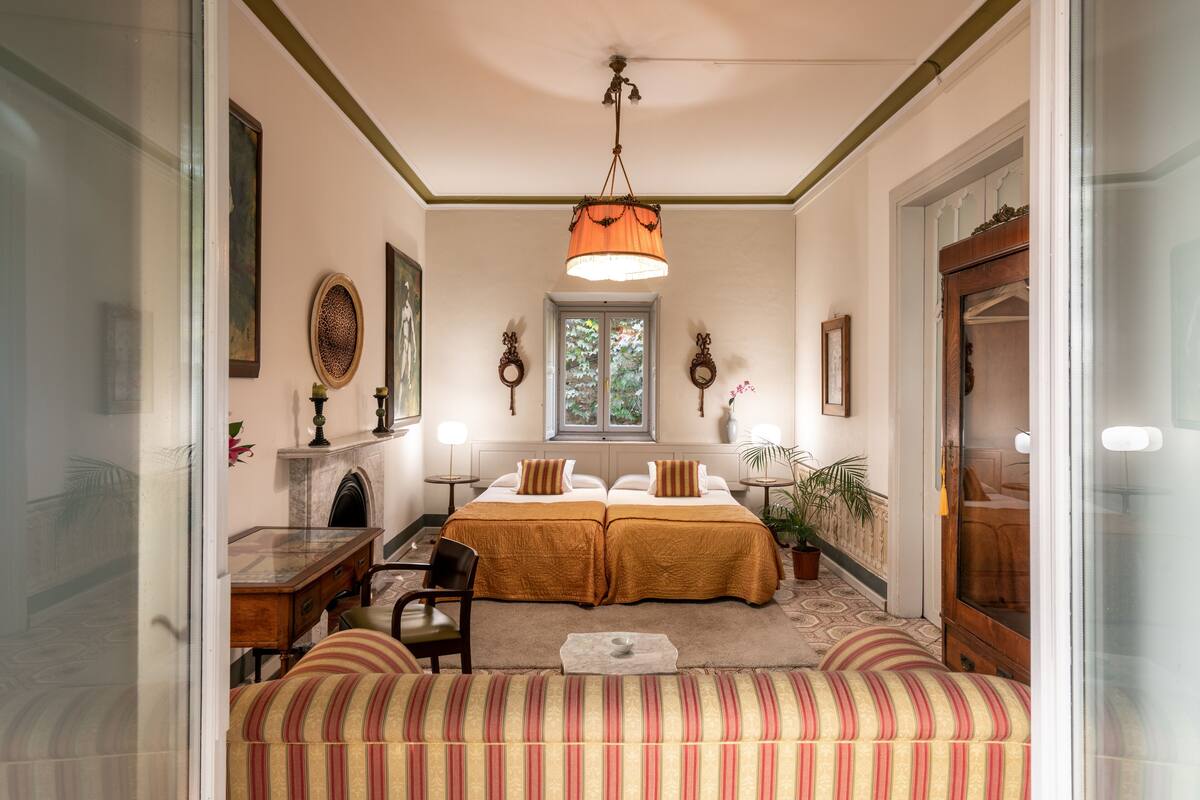 Habitació amb un llit doble, escriptori, cadira, sofà, finestra i porta.