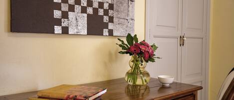 Un escritorio de madera con un libro, un jarrón de flores y un cuenco.
